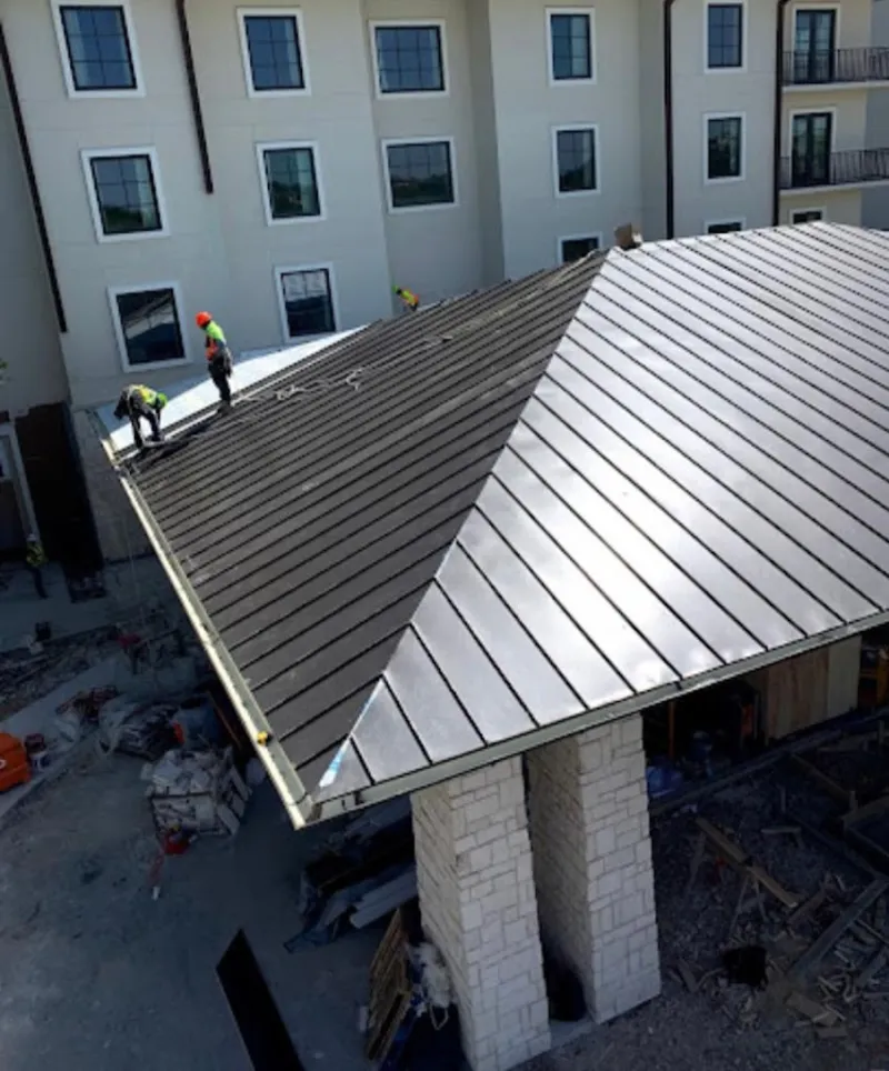 Crew installing standing seam metal roof panels on a commercial project in Woodlake